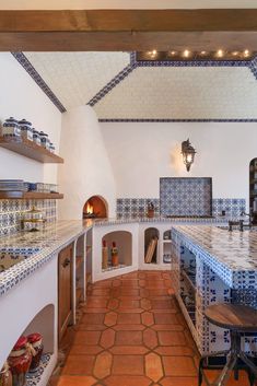 a kitchen with blue and white tiles on the walls, counter tops and ovens