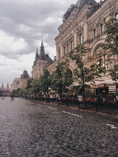 a cobblestone street lined with buildings and trees