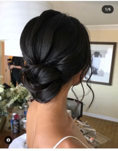 a woman with black hair in a low bun updo and flowers on the table