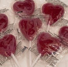 four heart shaped lollipops wrapped in plastic wrappers with toothpicks