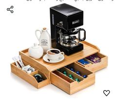 a coffee maker and some cups on a wooden tray with drawers underneath it that hold various items