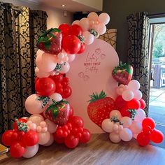 the balloon arch is decorated with strawberries and balloons