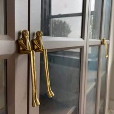 two golden handles on the front door of a house with glass doors and windows behind them