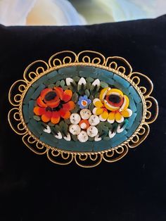 A beautiful example of Italian micro mosaic jewelry with vibrant colors of deep orange, bright yellow, white, dark green, and blue surrounded by a deep turquoise all encased within a goldtone filigree border.  The perfect piece on a jacket lapel, scarf, purse/briefcase, or even in your hair!  This item is in excellent vintage condition; pre-owned with no known chips, cracks, missing mosaic pieces, or repairs and no color or pattern distortions. Measures approx. 1.25"L (top to bottom) x 1.63"W (l Multicolor Cabochon Brooch As Gift, Multicolor Cabochon Brooch For Gift, Multicolor Cabochon Brooches As Gift, Multicolor Cabochon Brooches For Gifts, Multicolor Cabochon Brooches For Collectors, Unique Multicolor Cabochon Brooches, Vintage Multicolor Flower Jewelry, Multicolor Flower-shaped Vintage Jewelry, Artistic Multicolor Brooches For Gift