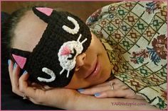 a woman is wearing a crocheted hat with a cat on it's face