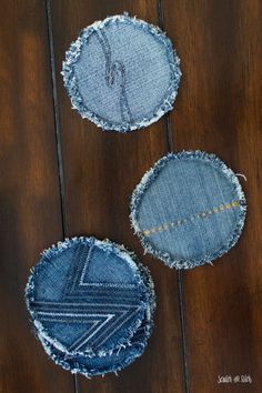 three pieces of denim sitting on top of a wooden floor next to each other with holes in them