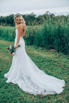 a woman in a wedding dress standing on the grass