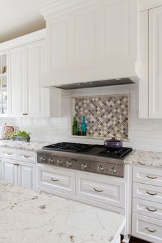 a kitchen with marble counter tops and white cabinets