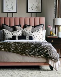 a bed with pink headboard and pillows on top of it next to two framed pictures