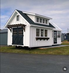 a small white house with a black door and windows on the side of it's roof