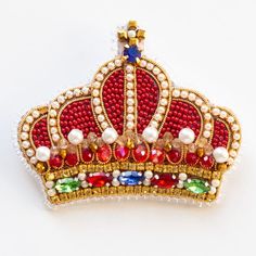 a red and gold crown brooch sitting on top of a white table