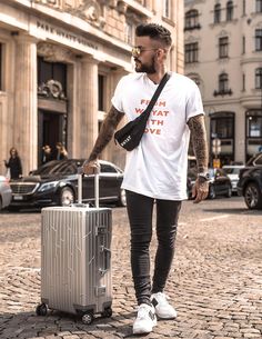 a man is walking down the street with his luggage and looking at something in front of him