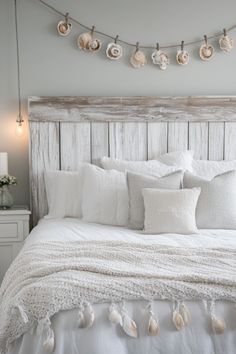 a bed with white linens and seashells on the headboard is shown