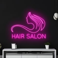 a neon sign that says hair salon in front of a black wall and white cabinet