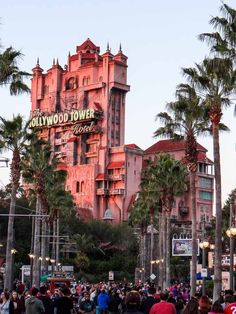 the hollywood tower hotel is surrounded by palm trees and people walking down the street in front