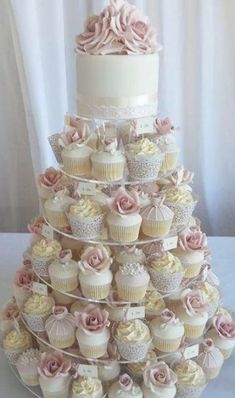 a tiered wedding cake with cupcakes on it