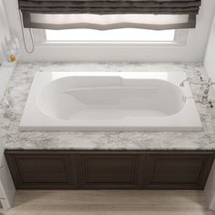 a white bath tub sitting under a window next to a sink in a bathroom with marble counter tops