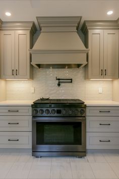 a stove top oven sitting inside of a kitchen next to white cupboards and drawers