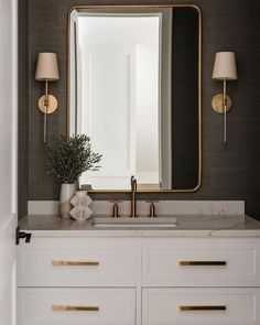 a bathroom vanity with a large mirror above it and two lamps on either side of the sink