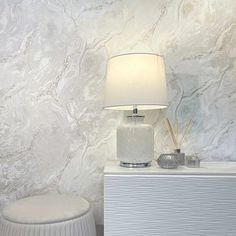 a lamp sitting on top of a table next to a white cabinet and stool with a light on it