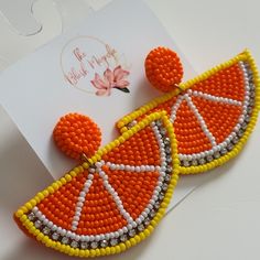 a pair of orange and yellow beaded earrings on top of a piece of paper