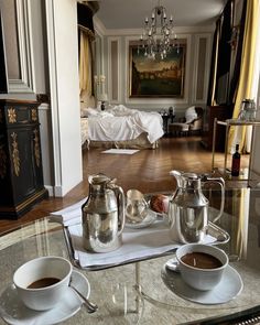 two cups of coffee are sitting on a tray in the middle of a hotel room