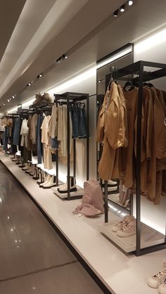 a row of clothes and shoes on display in a clothing store with lights above them