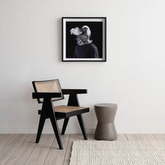 a black and white photo hangs on the wall next to two chairs in a room