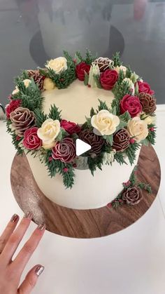 a woman is holding a knife over a cake with roses on it and greenery around the edges