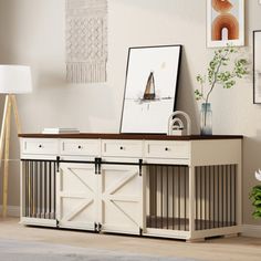 a living room with white furniture and pictures hanging on the wall, including a sideboard