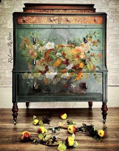 an old dresser with flowers painted on the front and sides, surrounded by leaves and apples