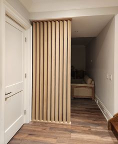 an open door leading to a bedroom with a bed in the corner and wooden flooring