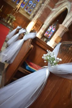 white flowers are tied to the pews at a wedding ceremony in an old church