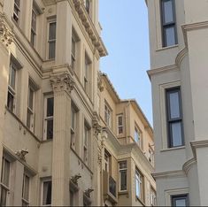 a clock on the side of a building in front of another building with many windows