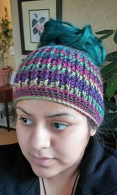 a woman with green hair wearing a colorful knitted beanie and looking at the camera