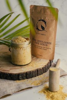 a bag of face scrub sitting on top of a piece of wood next to a wooden spoon