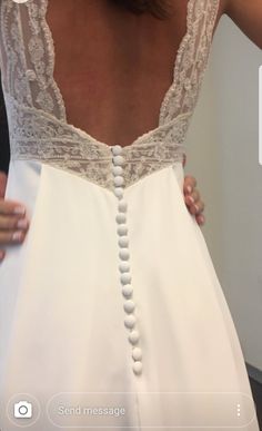 the back of a woman's wedding dress with beaded trims and buttons