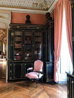 a pink chair sitting in front of a black cabinet