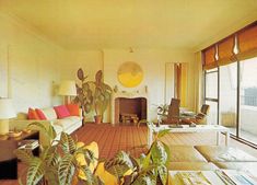 a living room filled with lots of furniture and plants in front of a fire place