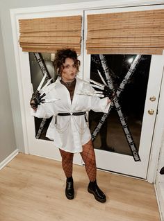 a woman standing in front of a door wearing tights and holding two pairs of scissors