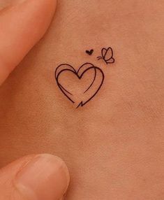 a small heart tattoo on the back of a woman's left side ribcage