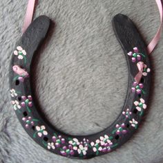 a black horseshoe with pink and white flowers on it sitting on top of a gray rug