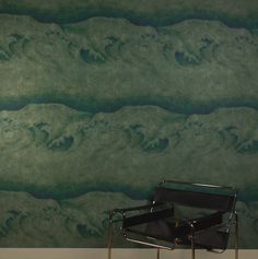 a chair sitting in front of a wall with waves painted on it