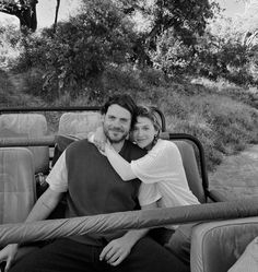 a man and woman are sitting in the back of a truck with their arms around each other