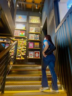 a woman standing at the bottom of stairs in front of a display case filled with cards