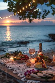 a table with food and wine on the beach