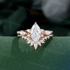 an engagement ring with a pear shaped diamond in the center and two smaller pear shaped diamonds on each band