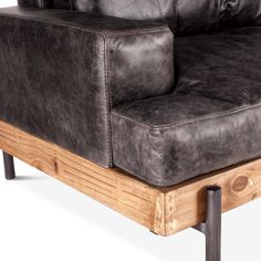 a brown leather couch sitting on top of a wooden frame