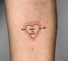 a heart tattoo with the words and here we are in love