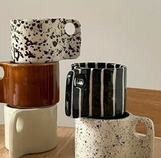 three ceramic mugs stacked on top of each other, one with black and white designs